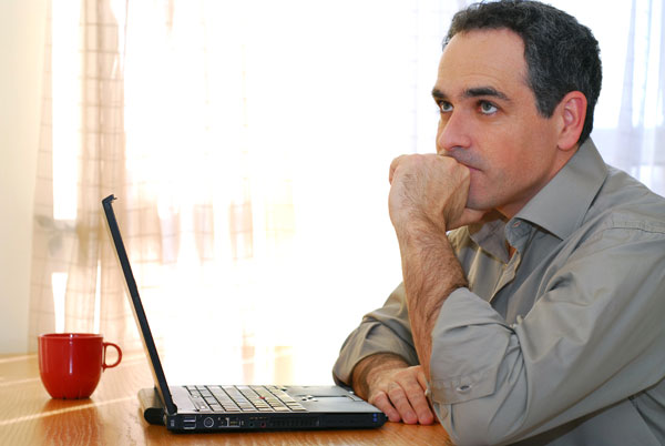 man contemplating communication from his Edmonton divorce lawyer on how to complete the separation from his former spouse and deal with issues such as child custody, child support and property division.